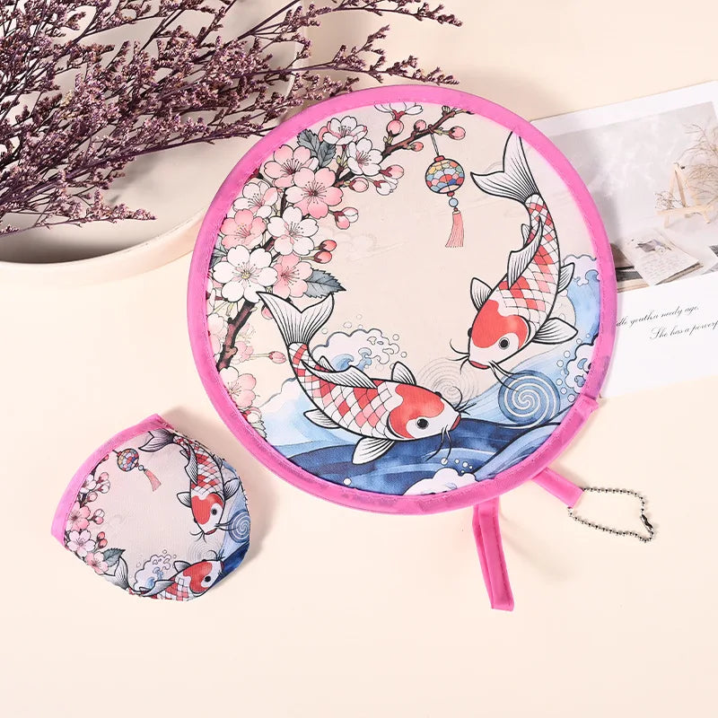 Pink fabric hand fan with a floral design and a hanging chain