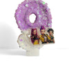 A purple glitter donut shaped candle featuring three anime characters.