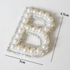 A white alphabet letter B made of pearl and rhinestone patches for clothing