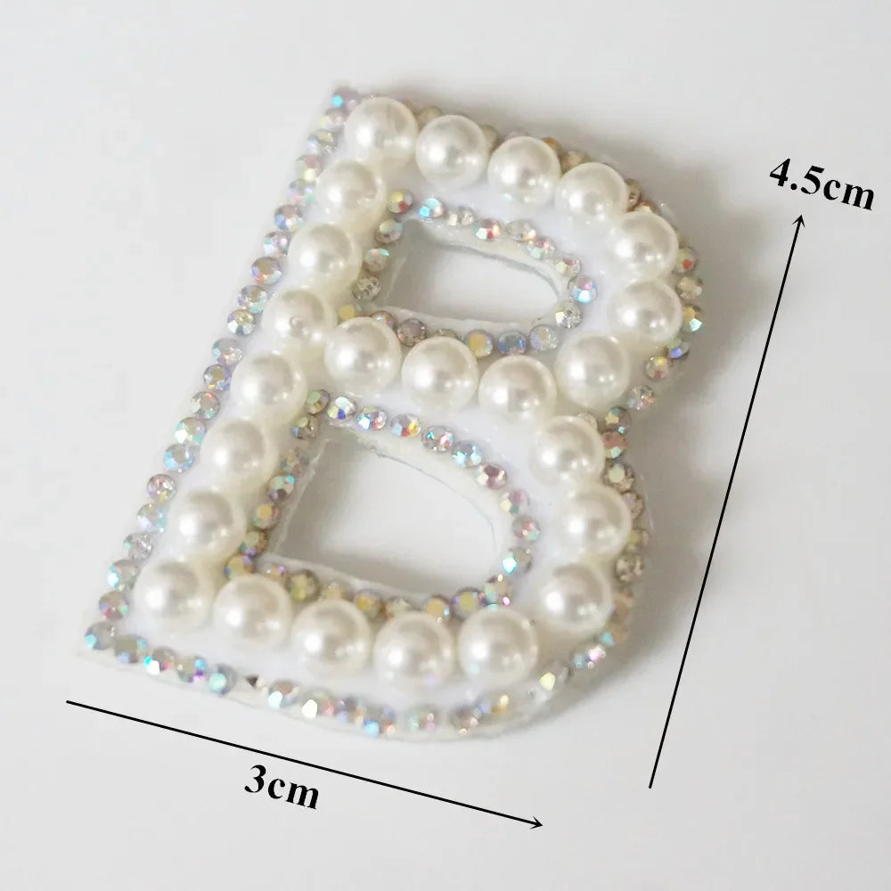 A white alphabet letter B made of pearl and rhinestone patches for clothing