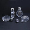 Clear glass bottle with a figurine and twist cap resting on a dark surface.