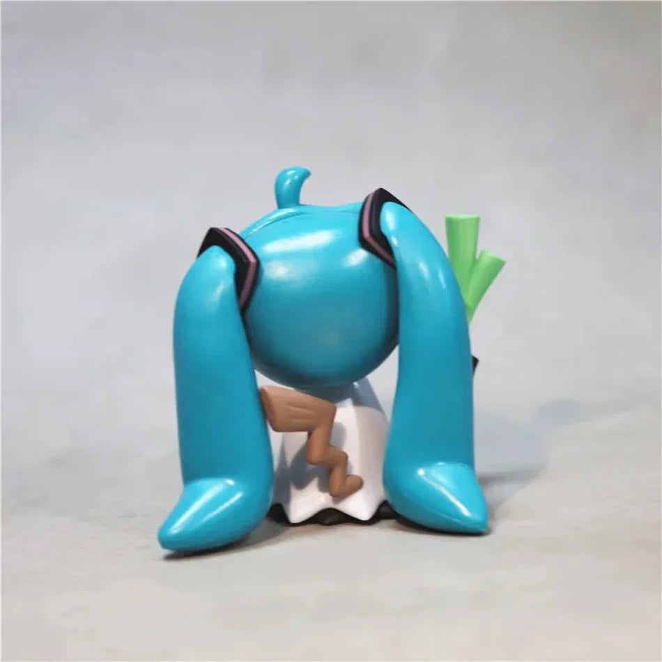A blue Hatsune Miku anime figurine with long blue hair and a green accessory.