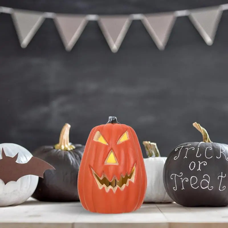 An orange carved pumpkin decoration with a menacing face displayed on a white surface.