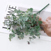 Green artificial fern and leaf sprigs arranged on a white background.