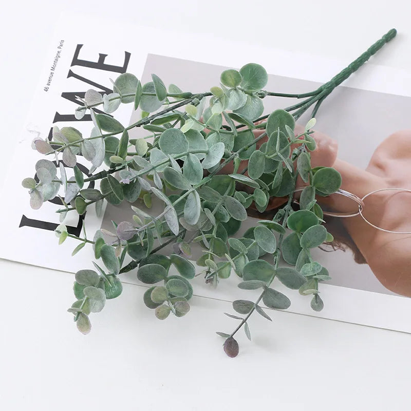 Green artificial fern and leaf sprigs arranged on a white background.