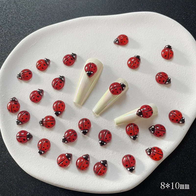A white oval dish holds a collection of small red and black ladybug resin charms for nail art.