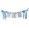 Light blue decorative birthday garland spelling out NEO with white textured letters and ribbons