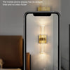 A mobile phone display showing a bright, vertical crystal LED light fixture illuminating a dark surface.