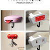 A display of various classic car headlight key holders with LED illumination in pink, red, and white.