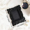 Black vintage resin mini picture frame with ornate detailing shown on a white surface.