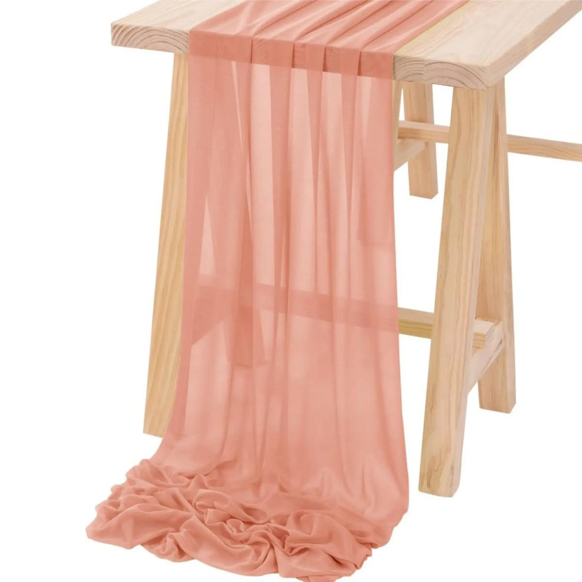 Pink chiffon fabric draped over a wooden table for an elegant backdrop or decor.