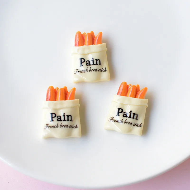 Trois aimants en forme de mini-baguettes de pain blanches avec des cure-dents oranges, étiquetés Pain français