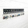 A black wall display rack featuring multiple silver and colored metal medals hanging on pegs.