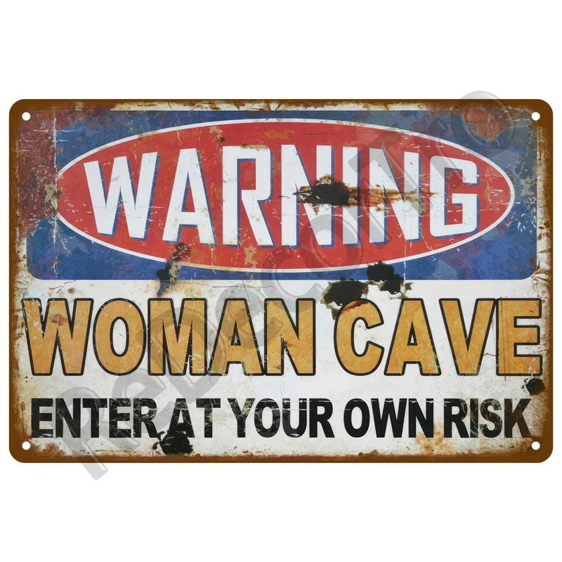 A vintage metal tin sign with a warning label that reads WARNING WOMAN CAVE ENTER AT YOUR OWN RISK