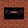 A black rectangular sign with the word tool in red glowing text mounted on a brick wall.