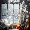 A decorated Christmas tree with white snowflake lights in front of a snowy window.