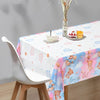 A white tablecloth decorated with pink and blue clouds, bears, and stars for a gender reveal party.