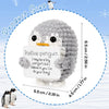 A gray and white crocheted penguin plush toy with an encouraging card, displayed within a circular guide.