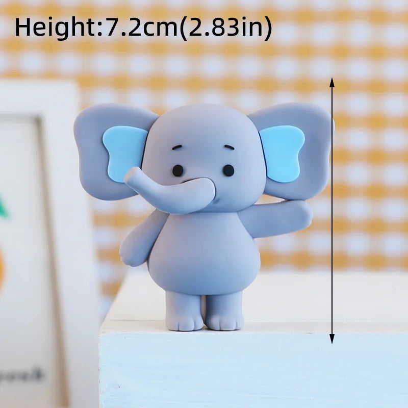 A gray cartoon elephant cake topper with light blue ears standing on a white surface.