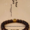 A close-up of a handcrafted Pixiu bracelet made with dark wood and semi-jade beads.
