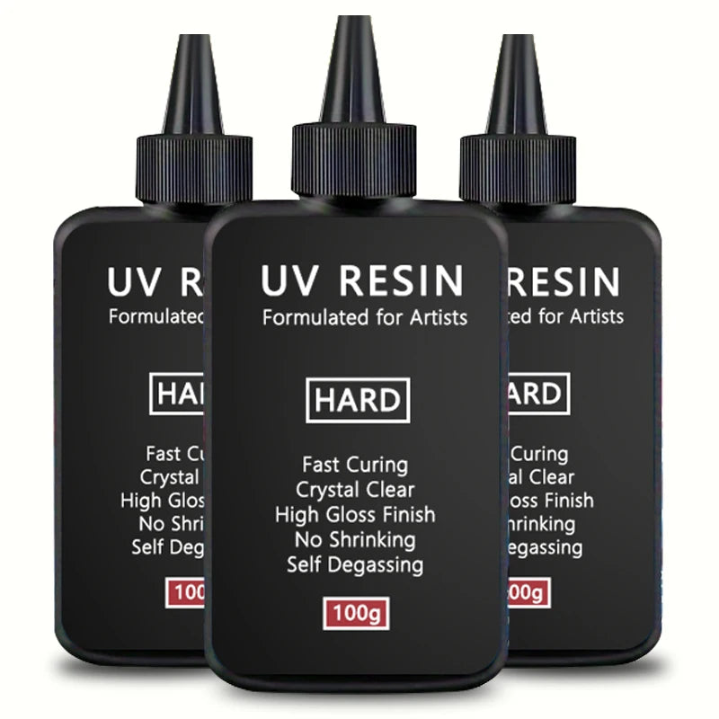 Three bottles of hard UV resin for artists with black dropper caps and labels