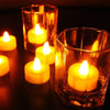 A set of glowing yellow LED tea light candles in glass holders on a dark surface.
