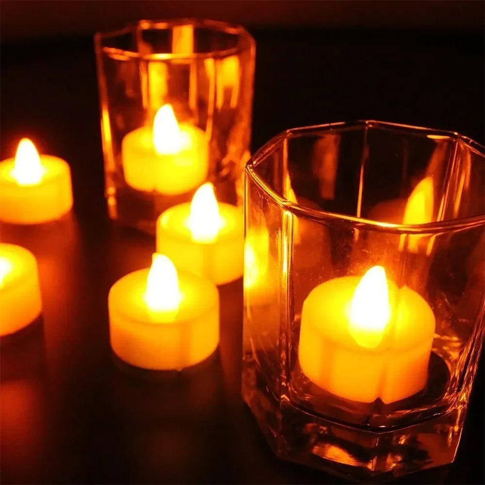 A set of glowing yellow LED tea light candles in glass holders on a dark surface.