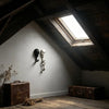A set of two black and white skull wall hooks mounted on a light gray wall in a rustic room.