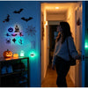 A woman stands in a hallway illuminated by glowing Halloween-themed wall stickers and decorations.