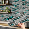 A hand holds a rectangular crystal film marble wall decal against a gray and teal subway tile background.