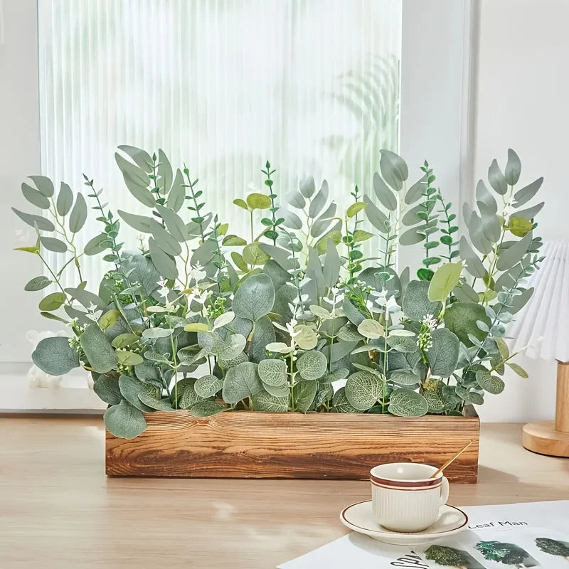A lush arrangement of mixed green eucalyptus and willow artificial flowers displayed in a wooden box.
