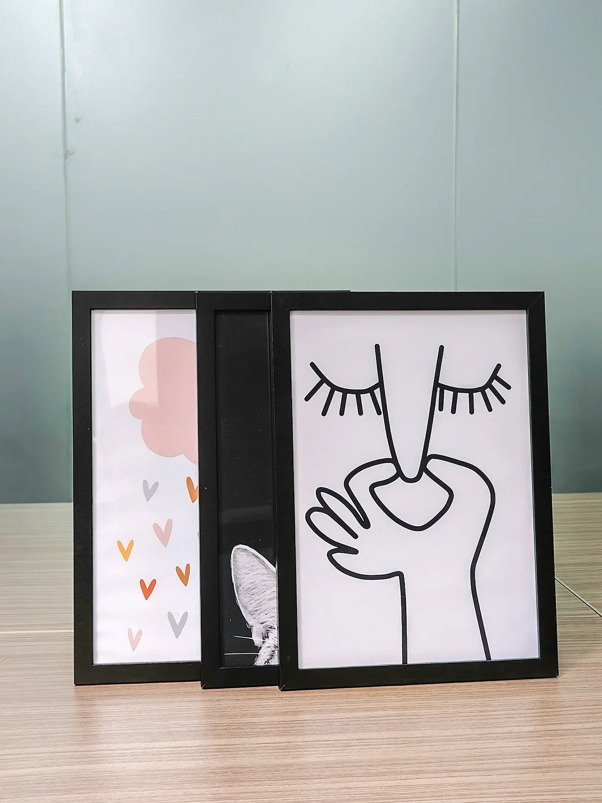 A set of three black picture frames with acrylic fronts displaying hand and abstract shapes.