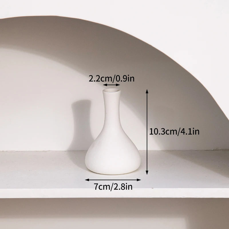 A white ceramic bud vase is displayed on a shelf, showing its dimensions.