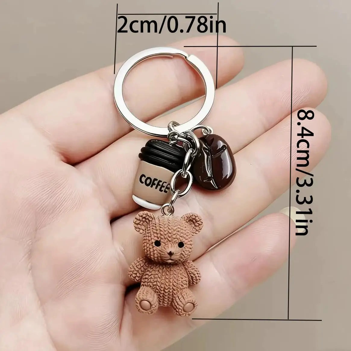 A small brown teddy bear charm attached to a silver keyring and a coffee-themed pendant.