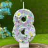 A purple number eight cake candle decorated with small flowers and a white butterfly on a white stand.