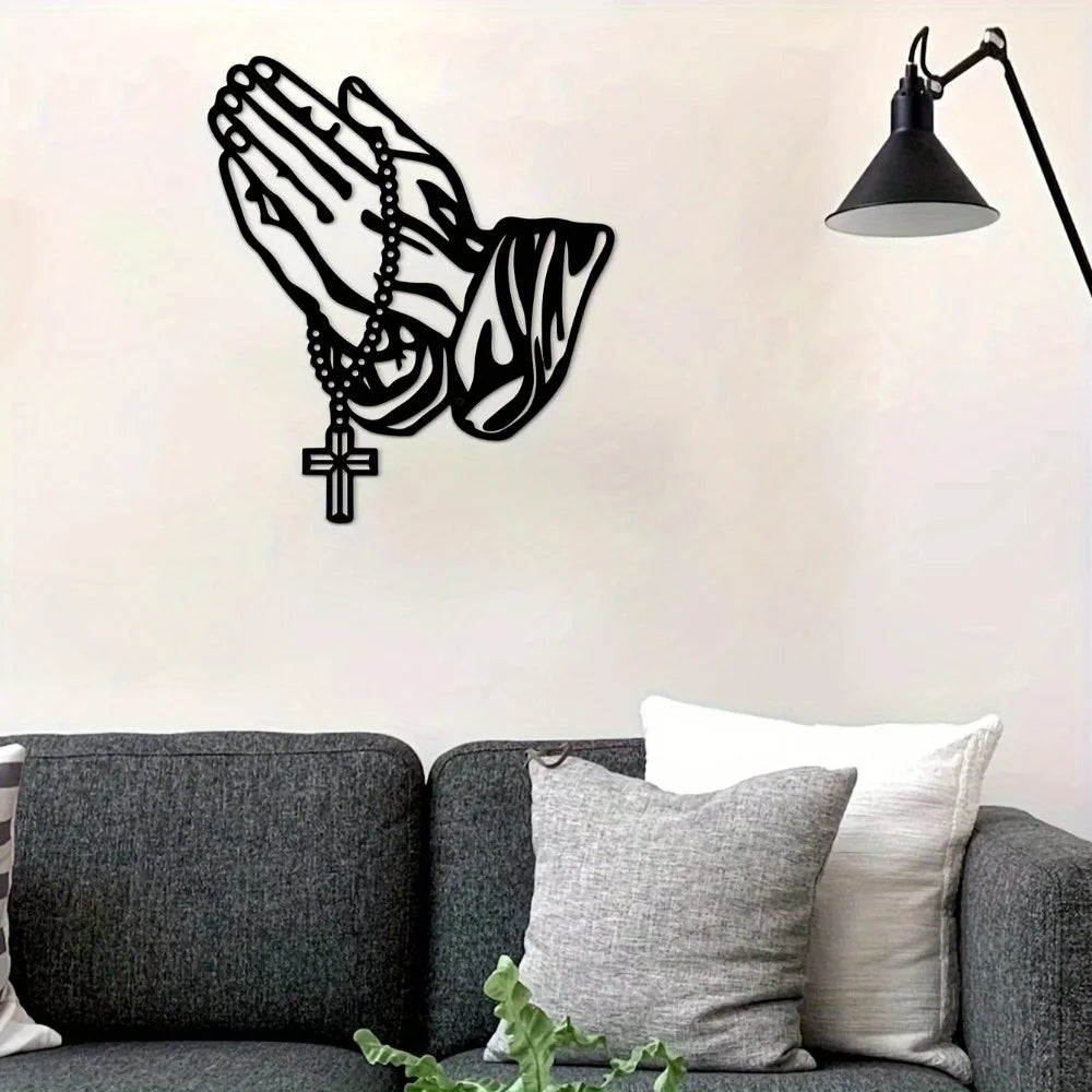 Black silhouette of an open hand with a prayer chain and cross, mounted as wall art.
