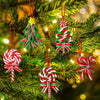 A close-up of green pine branches decorated with red and white candy cane Christmas ornaments.