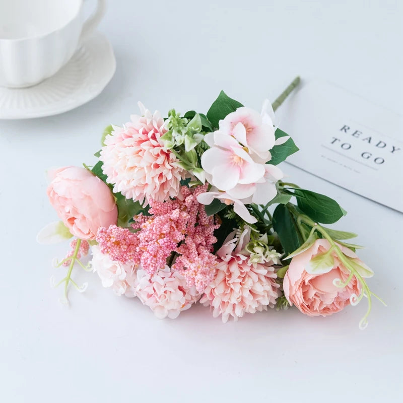A bouquet of pink and peach artificial silk peony flowers arranged on a white surface.