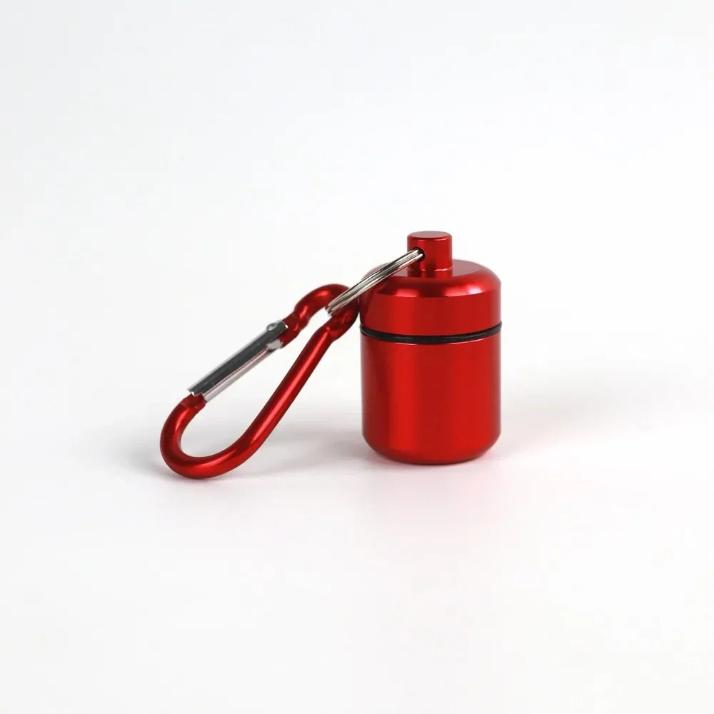 A small, red pill organizer is attached to a silver keyring.