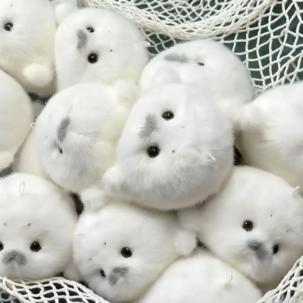 A collection of small white seal plush keychains nestled in a white mesh bag.