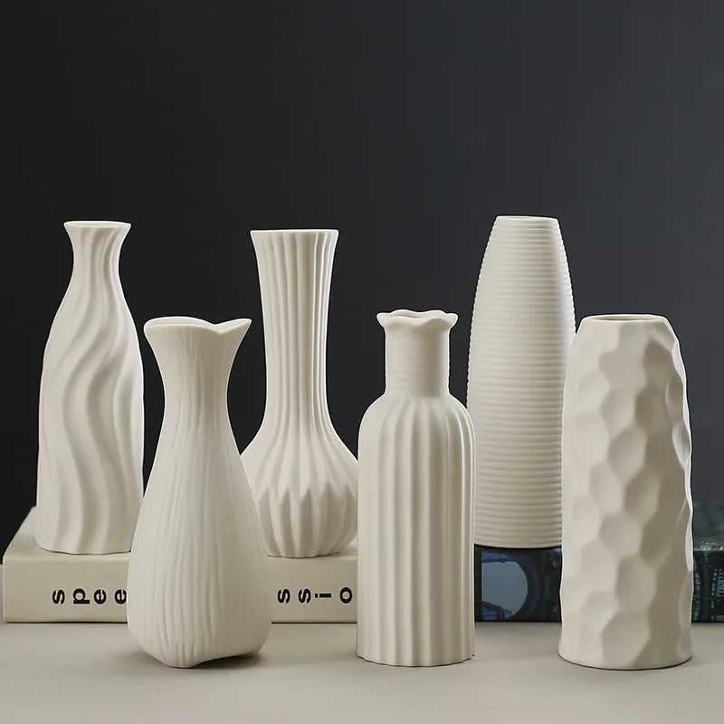 A collection of white ceramic desktop vases featuring an organic ripple design, displayed against a dark background.