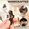 A hand holds a dark wooden pocket cross, highlighting its handcrafted nature and durability.