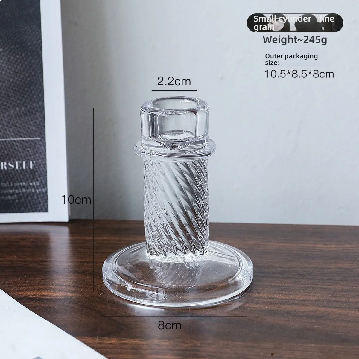 Elegant clear glass pillar candle holder with a textured design shown on a wooden surface.