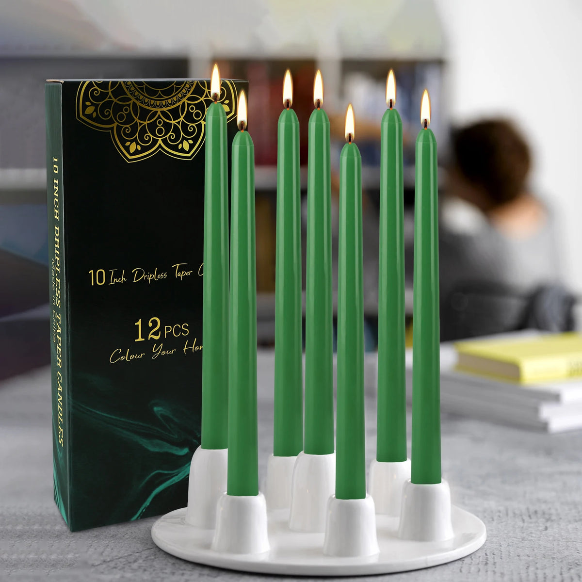 A display of twelve green drip-less taper candles in white holders on a white plate.