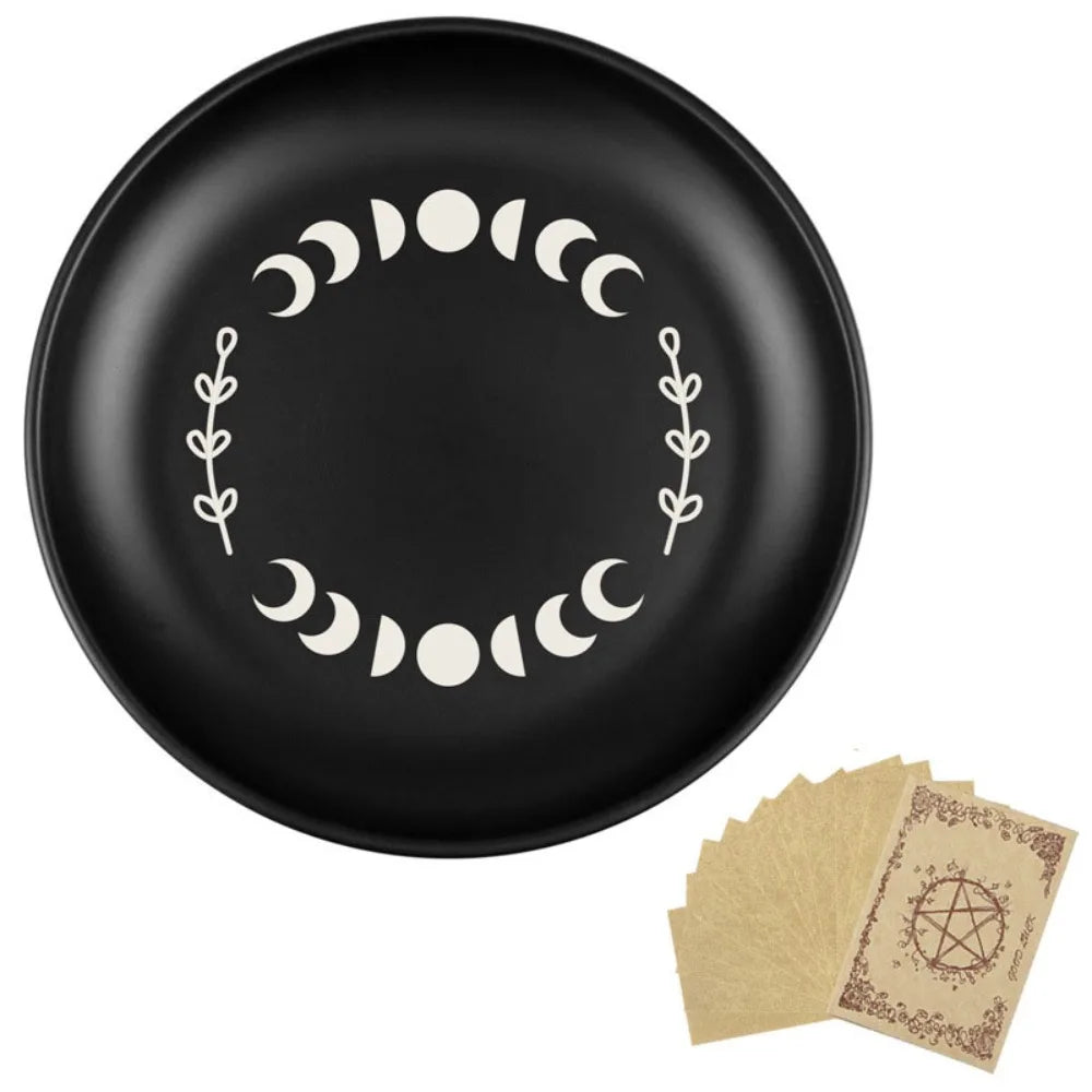 Un plat décoratif noir avec un motif circulaire de lunes et de vignes feuillues.