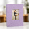 A purple linen photo album with a square display window showing a couple embracing.
