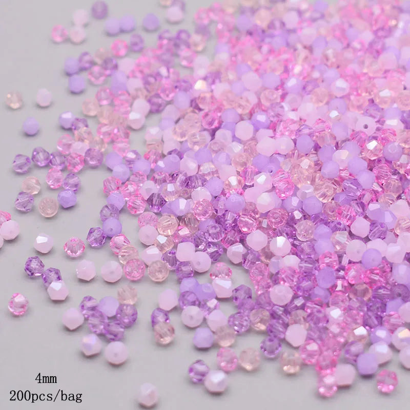 A pile of faceted bicone glass beads in mixed shades of pink and purple for jewelry making