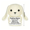 A white crocheted bunny doll with a positive message card attached.