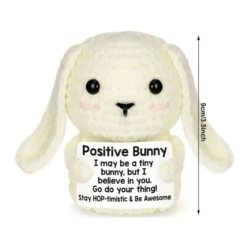 A white crocheted bunny doll with a positive message card attached.