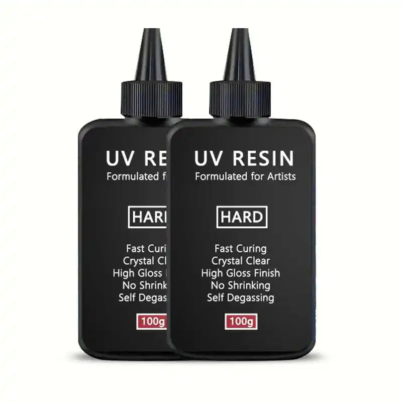 Two black dropper bottles of UV resin formulated for artists with labels indicating fast curing and no shrinking